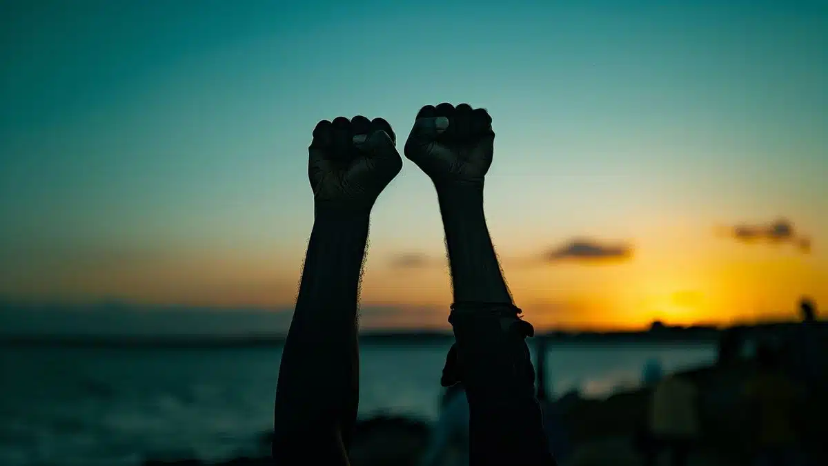 Silhouette of raised fists against the evening sky near La Rochelle.